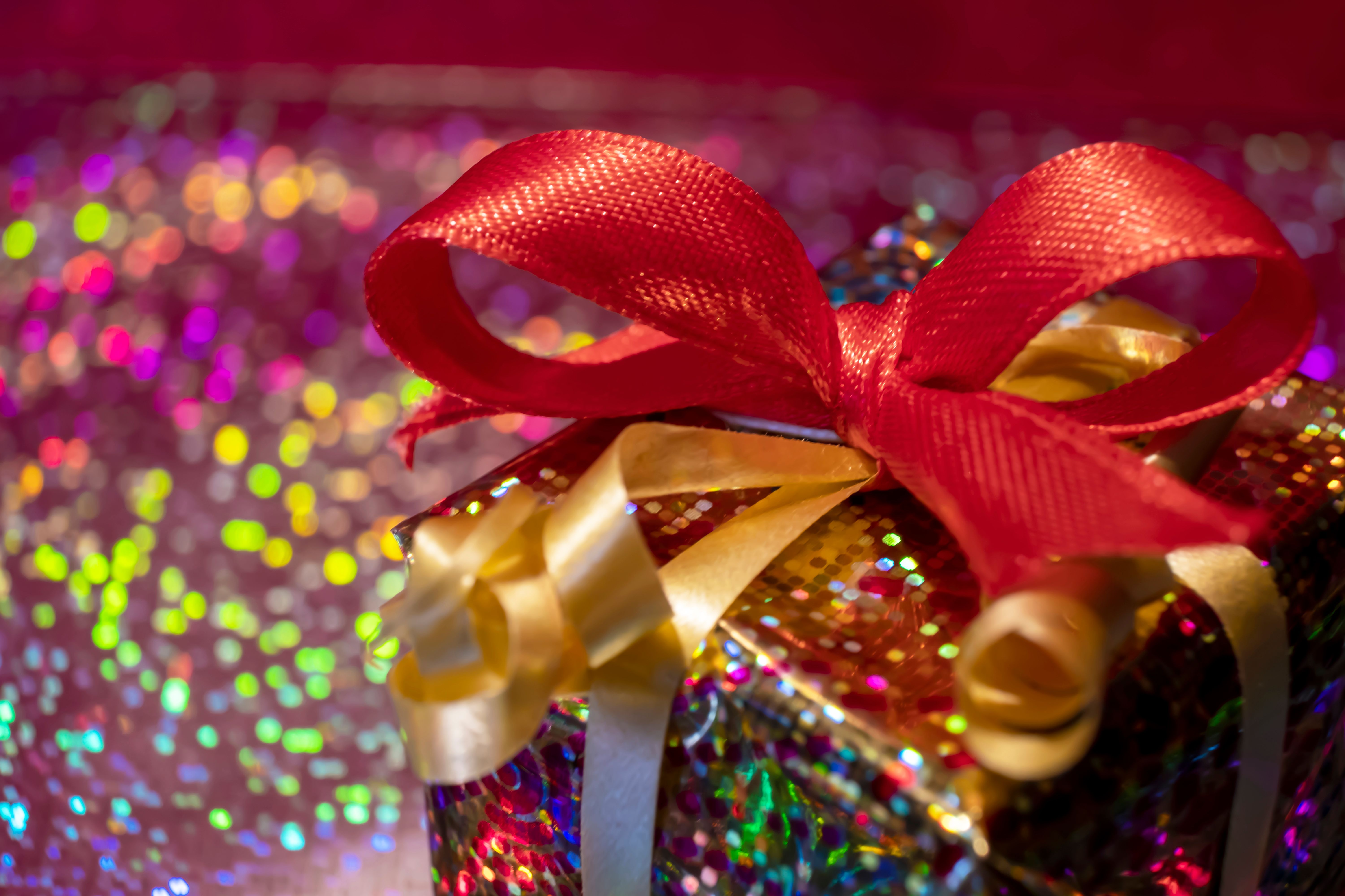 Beautifully wrapped gift with a red ribbon and glittery paper